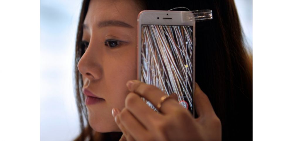 Une femme teste une caméra qui permet une vision microscopique de ses cheveux, au Congrès mondial de la téléphonie mobile de Barcelone, le 24 février 2016